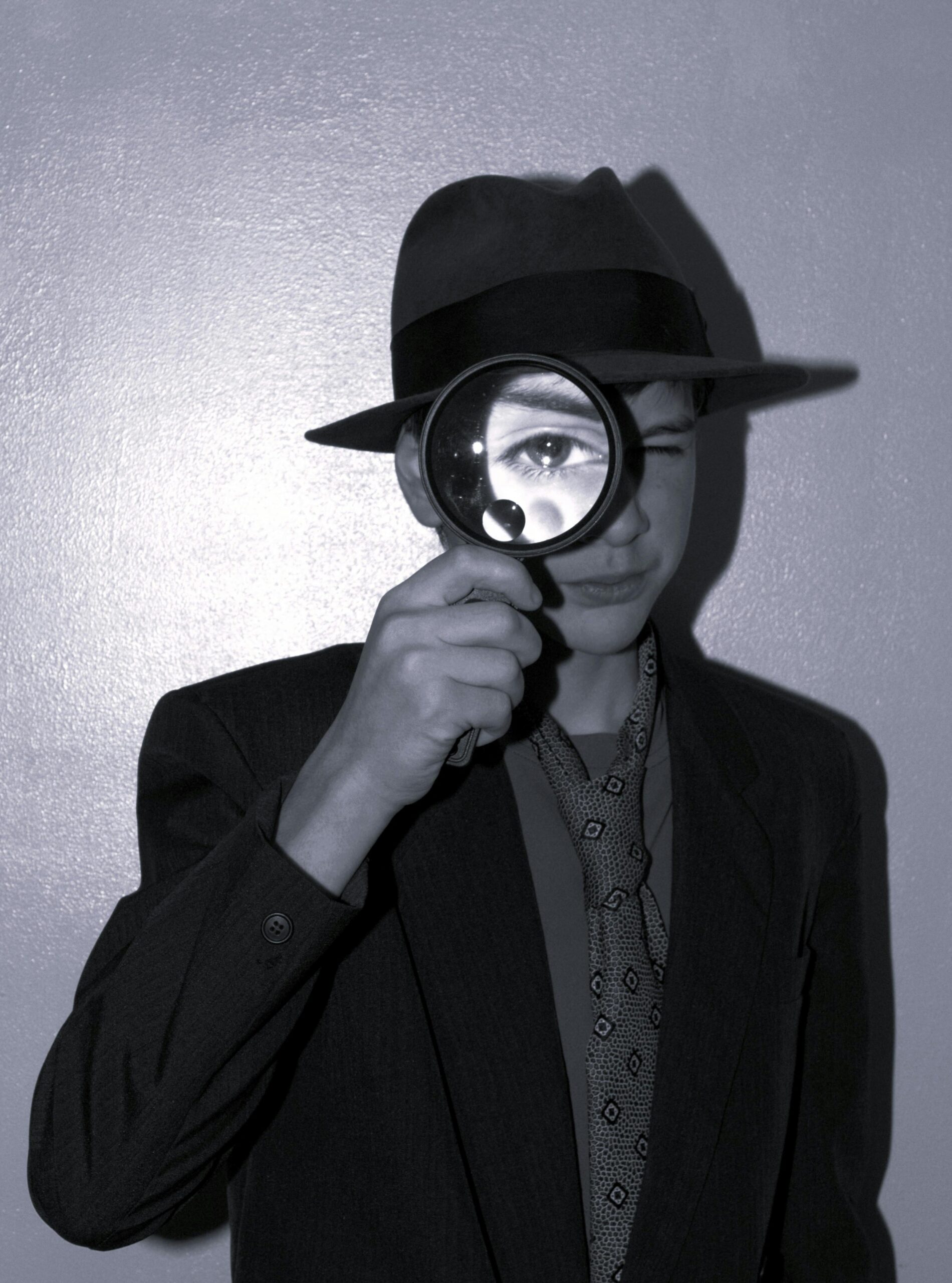A teenager in vintage attire holds a magnifying glass, evoking a classic detective mood.